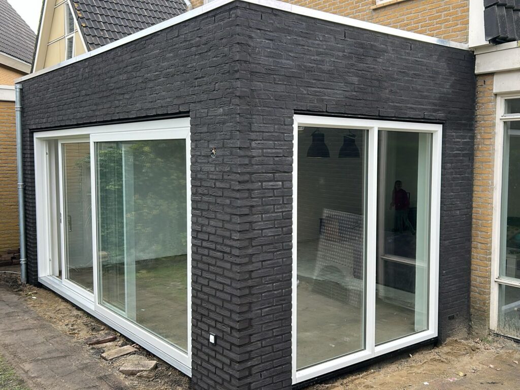 Klassieke aanbouw aan jaren 30 woning met baksteen en houten kozijnen