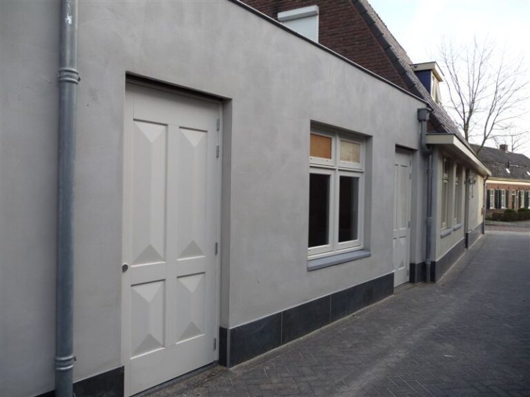 Strak afgewerkte zijgevel van woning in Gouda met witte deuren en grijze gevelplint