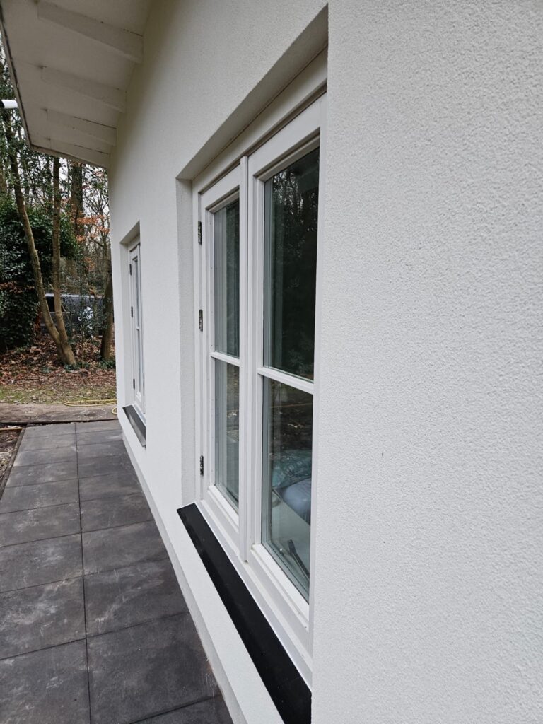 Vernieuwde witte zijgevel met lichte kozijnen en zwarte raamdorpels